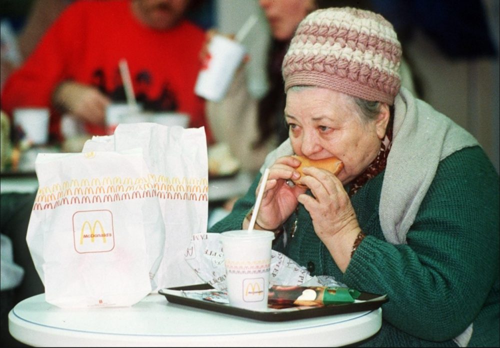 1990. Пожилая женщина ест гамбургер в день открытия первого МакДональдса. 31 января.jpg